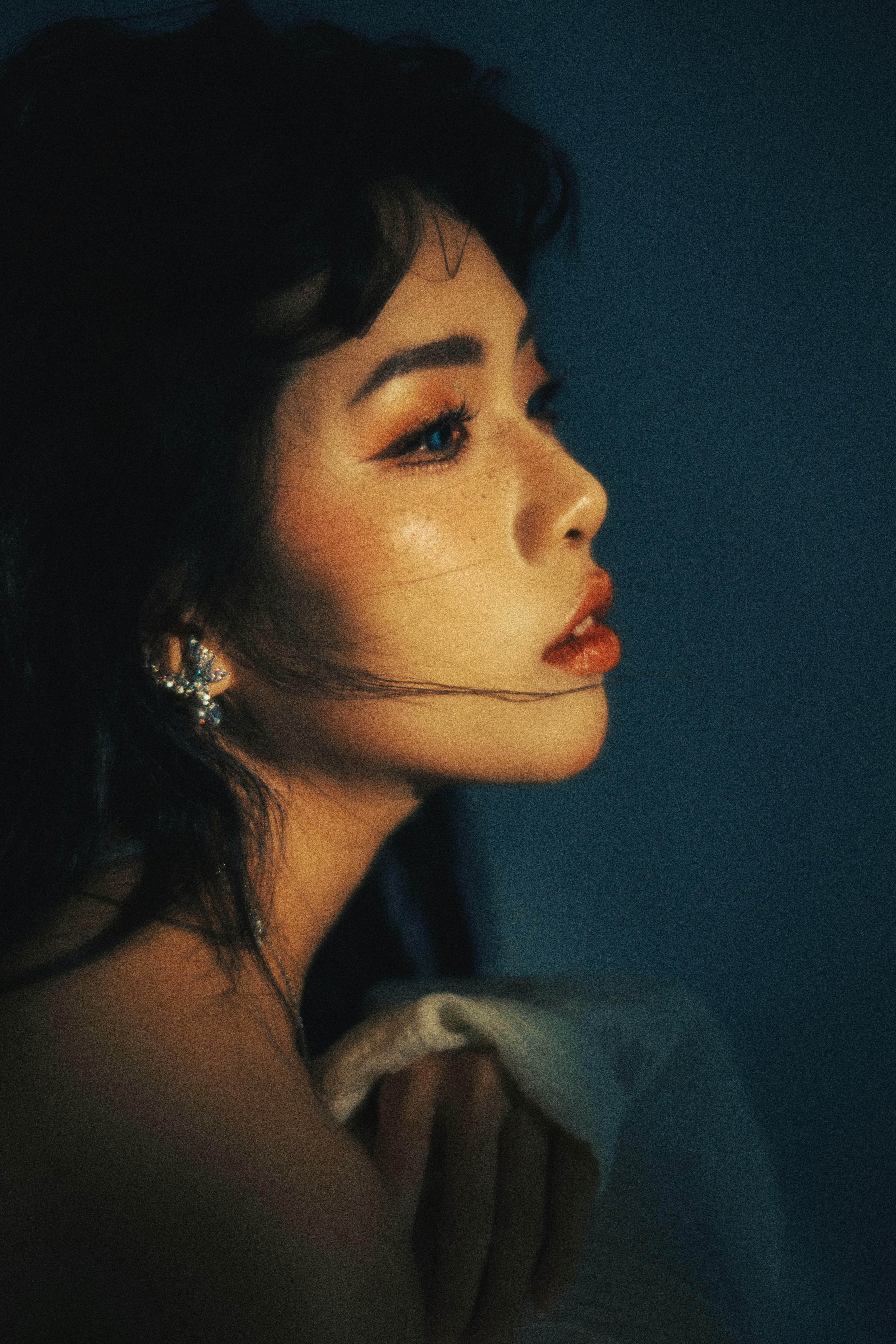 Profile portrait of a woman with dramatic lighting and soft tones, evoking a moody atmosphere.