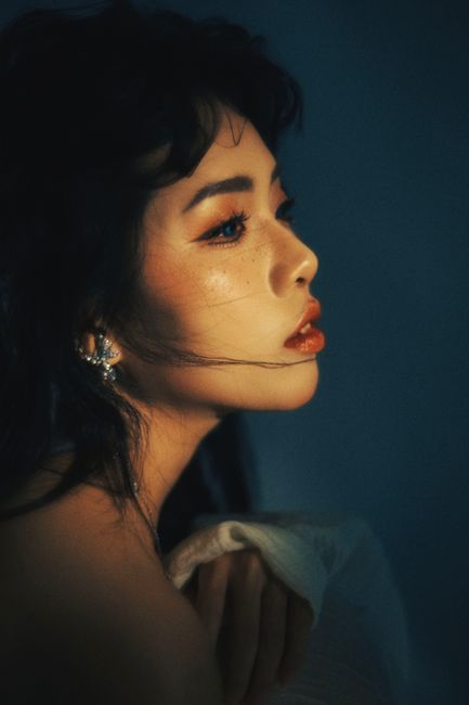 Profile portrait of a woman with dramatic lighting and soft tones, evoking a moody atmosphere.