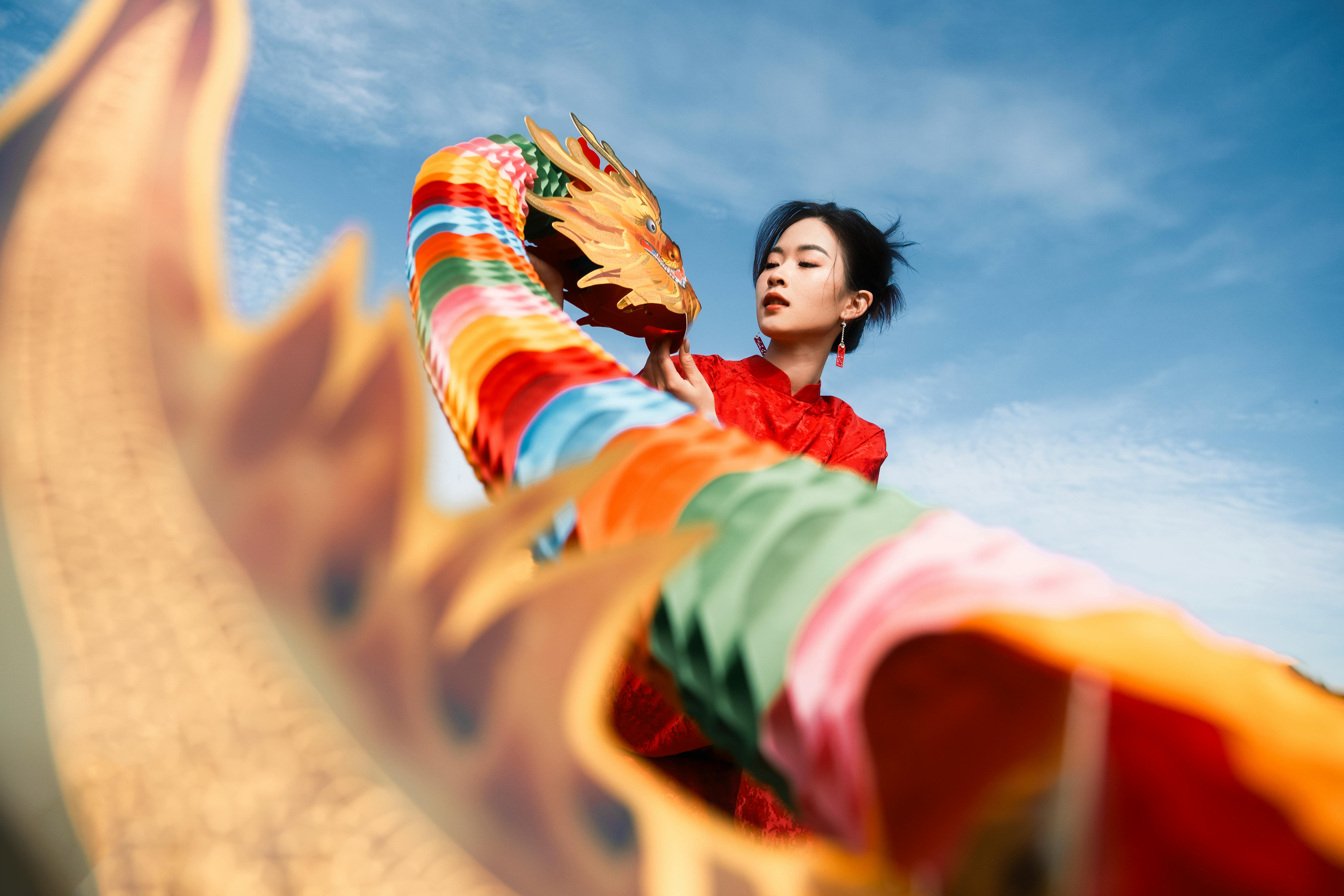 A colorful dragon dance performer in traditional attire against a clear blue sky, celebrating culture.