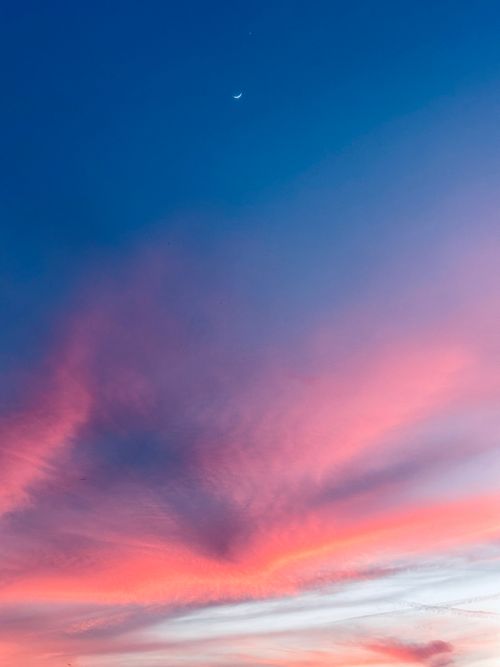 Free Vivid sunset sky with crescent moon and colorful clouds casting a serene mood. Stock Photo