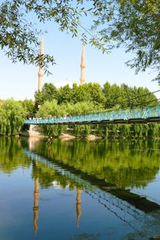 A picturesque scene of a bridge and mosque reflection in a peaceful river in Türkiye.