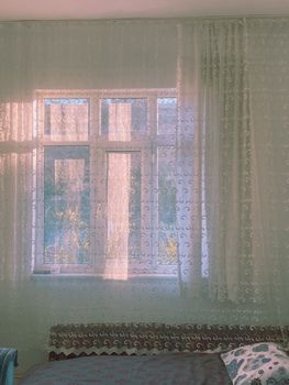 A serene indoor scene featuring sunlight streaming through lace curtains in a Turkish home.