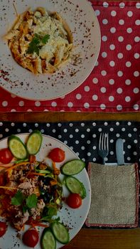 Top view of pasta and salad dishes set on polka dot tablecloths, perfect for a quaint meal setting.