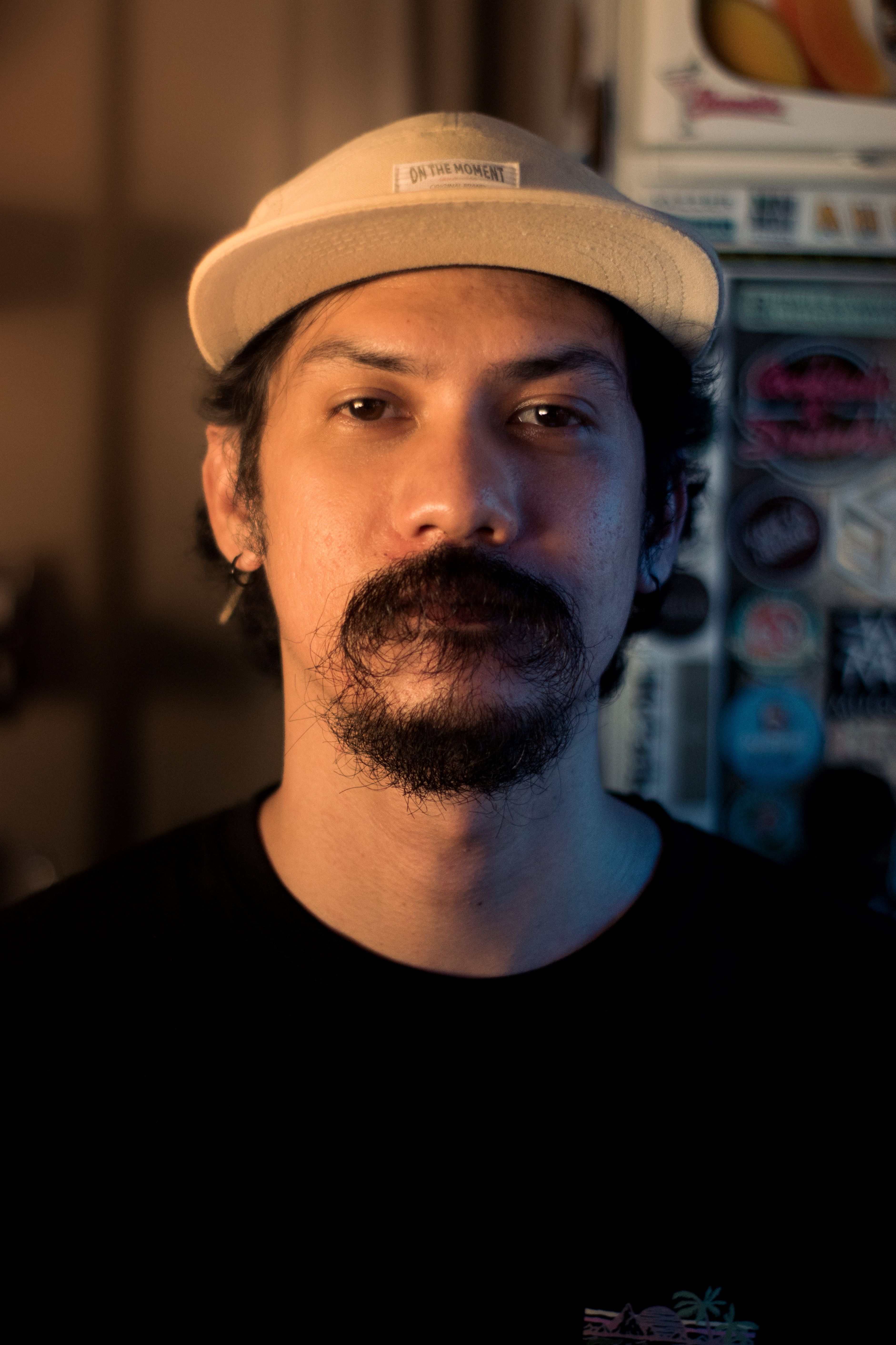 Bearded man wearing a cap, posing indoors, casual and relaxed ambiance.