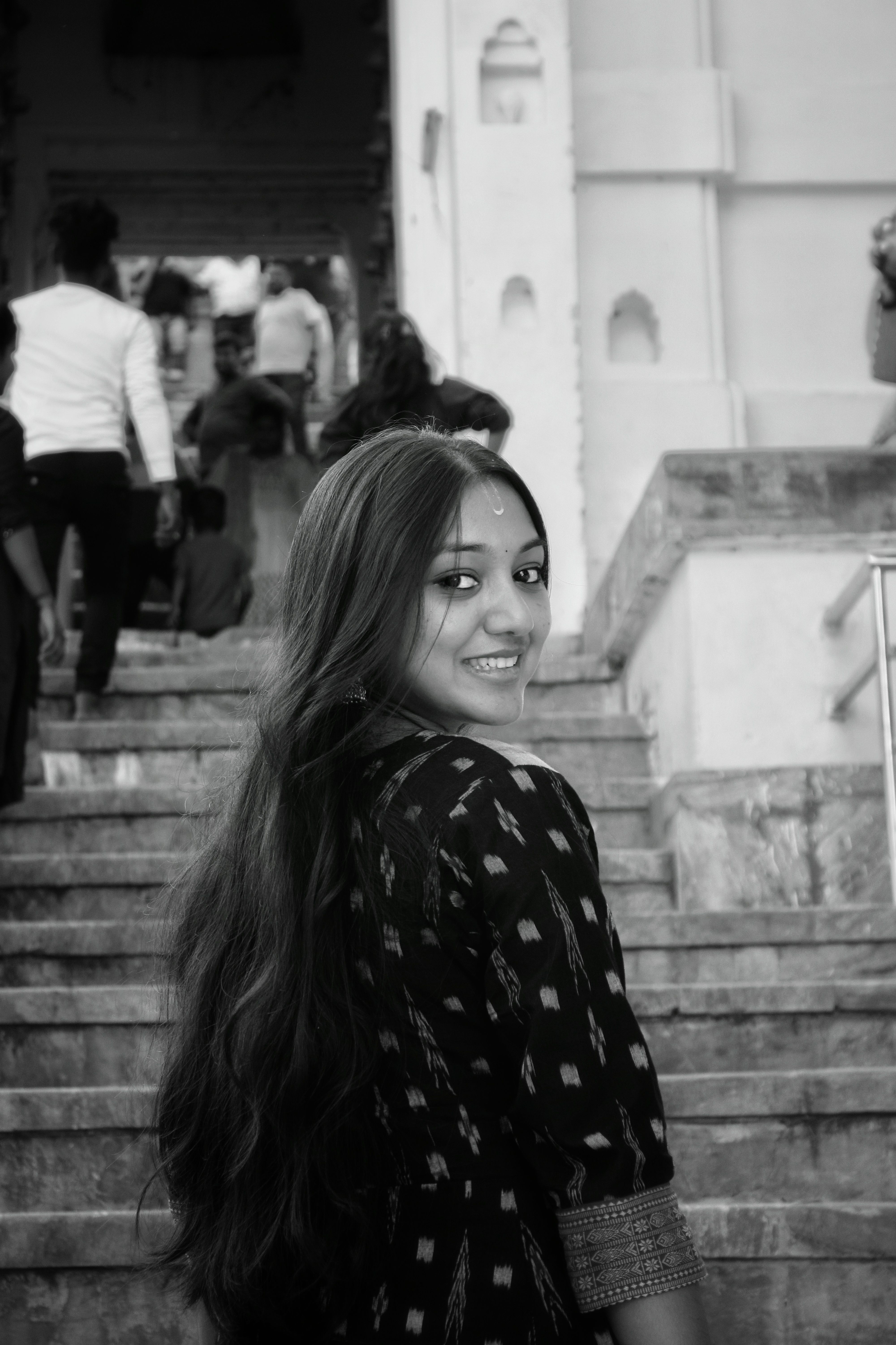 Smiling young woman in traditional attire on steps, Odisha, India.