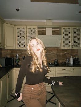 Casual portrait of a young woman in a modern kitchen with beige cabinets and a classic vibe.