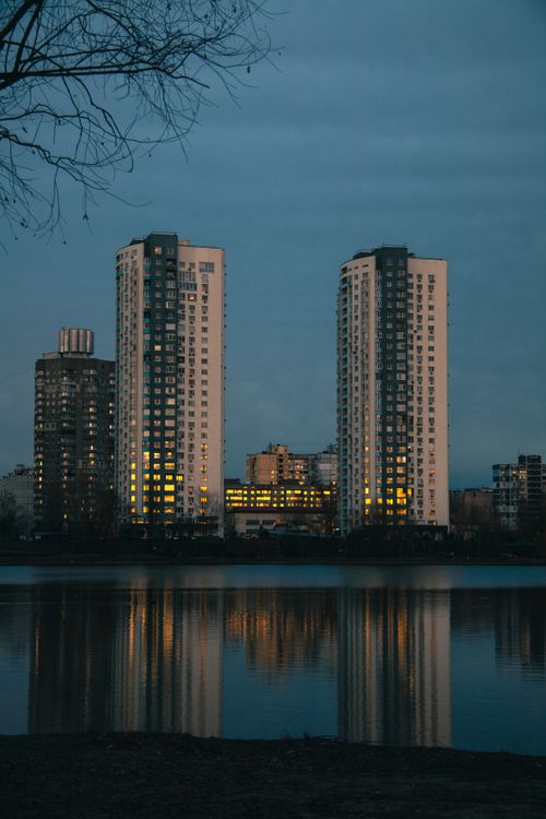 Free Tall buildings reflecting on a calm lake at twilight, showcasing urban architecture and serene vibes. Stock Photo