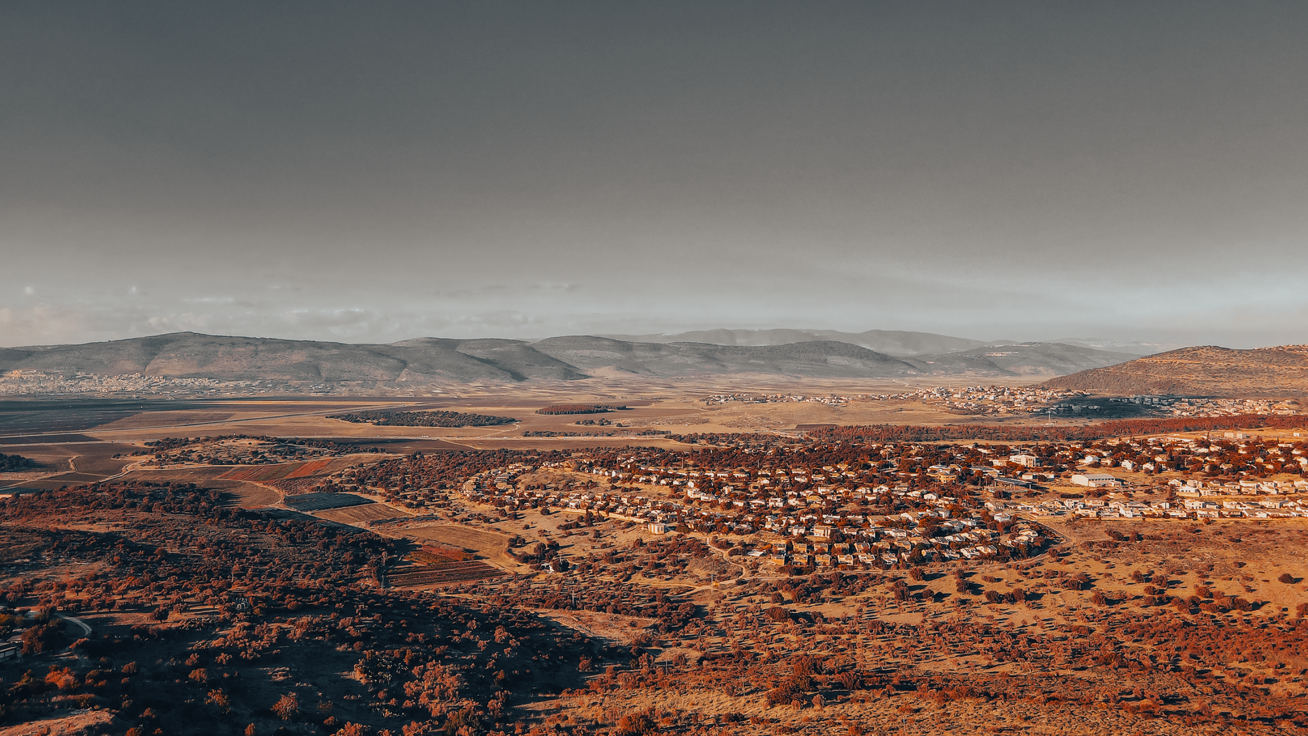 Aerial shot of North District, Israel, showcasing hills and residential areas under a warm sky.