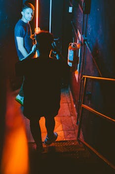 Two adults in a dimly-lit Buenos Aires club hallway, neon lights enhancing the scene.