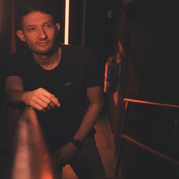 Young man leaning on a dimly lit bar railing in Buenos Aires, Argentina.