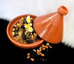 Delicious Moroccan lamb tagine with almonds, prunes, and quail eggs in a clay pot.