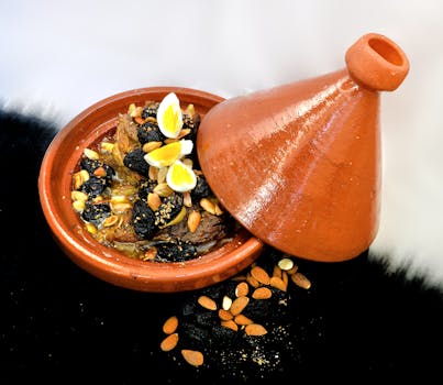 Delicious Moroccan lamb tagine with almonds, prunes, and quail eggs in a clay pot.