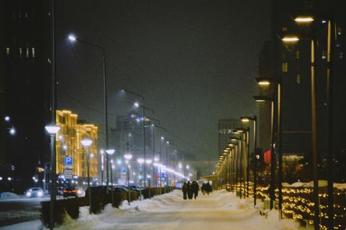 Free A snowy winter night street scene in Astana, Kazakhstan with illuminated buildings and streetlights. Stock Photo