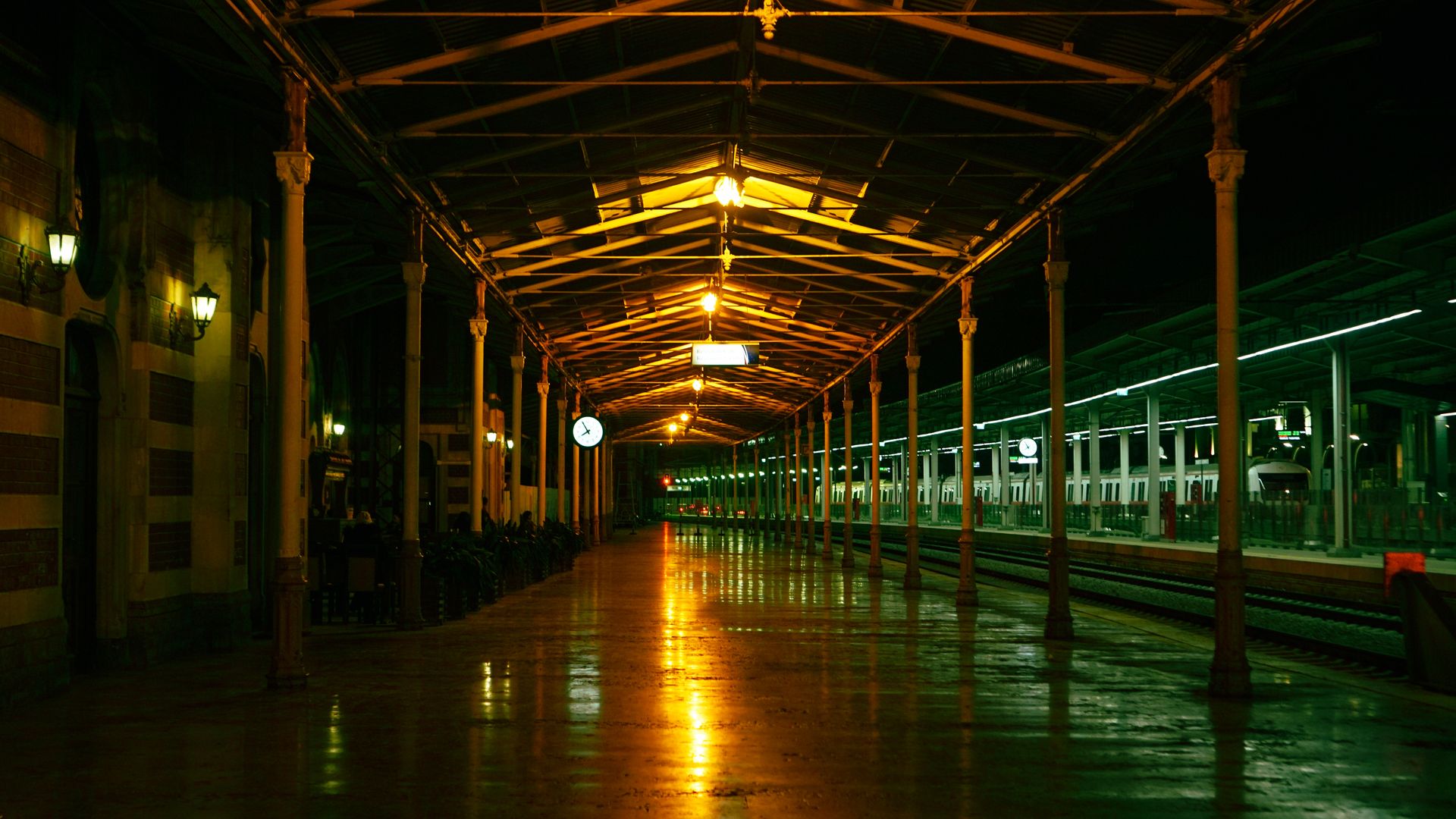 Empty vintage train station illuminated by warm lights at night, creating a nostalgic atmosphere.
