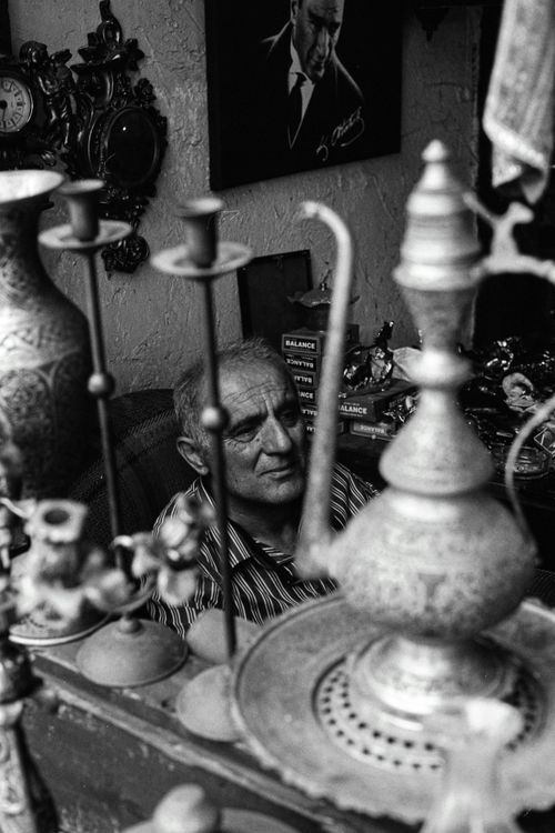 Free Black and white portrait of an elderly man surrounded by vintage decor in a Safranbolu shop. Stock Photo