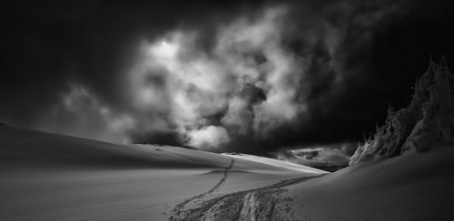 Free Captivating black and white shot of a snowy landscape beneath dramatic storm clouds. Stock Photo