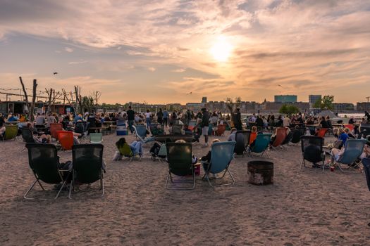 People enjoy a relaxing evening at a sandy beachfront in Copenhagen with a vibrant atmosphere.