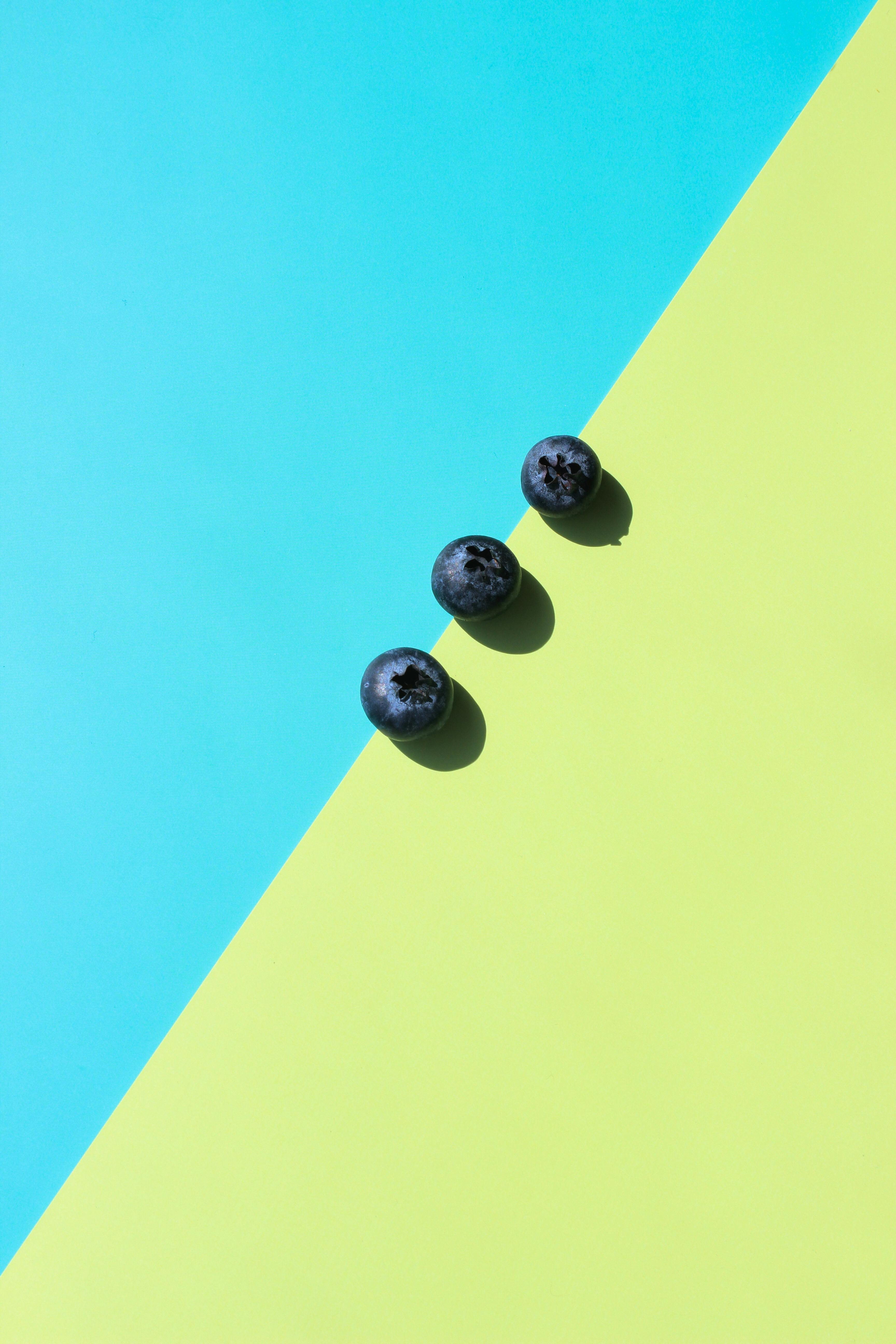 Miễn phí Ba quả việt quất được đặt trên nền chéo hai tông màu xanh và vàng. Ảnh lưu trữ