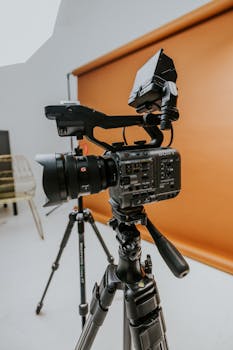 High-quality cine camera setup in a modern studio environment with orange backdrop.