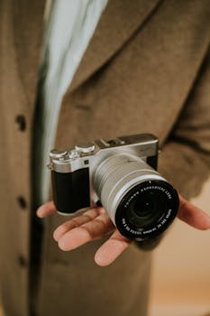 A stylish camera held in hand, showcasing advanced lens details. Perfect for photography themes.