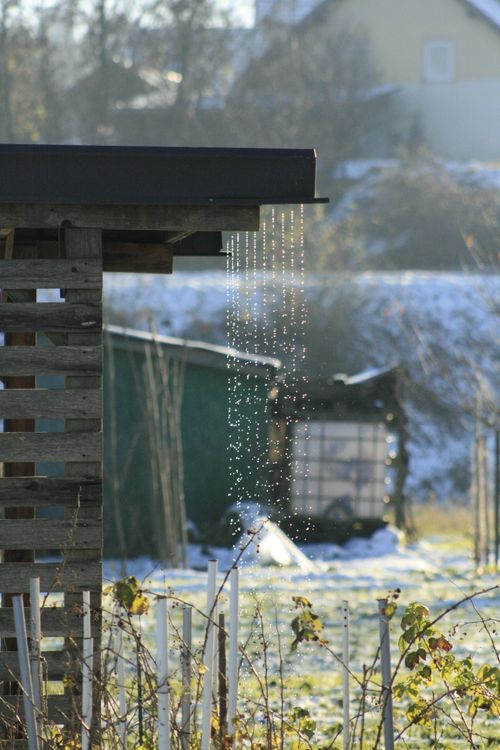 Free Snow melting from a rooftop creating droplets, winter garden scene. Stock Photo