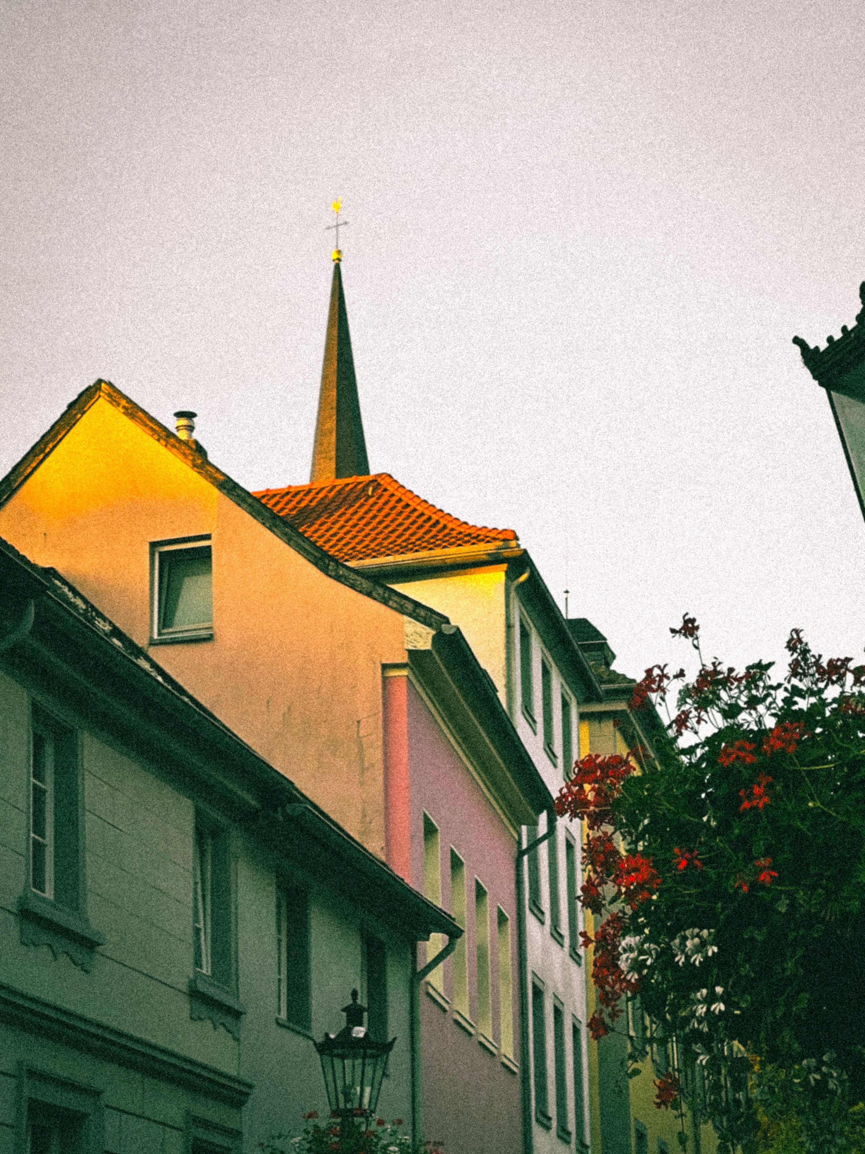 Warm sunset light on colorful buildings and church spire in Ratingen, Germany.