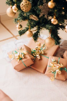 Beautifully wrapped presents with golden bows under a decorated Christmas tree.