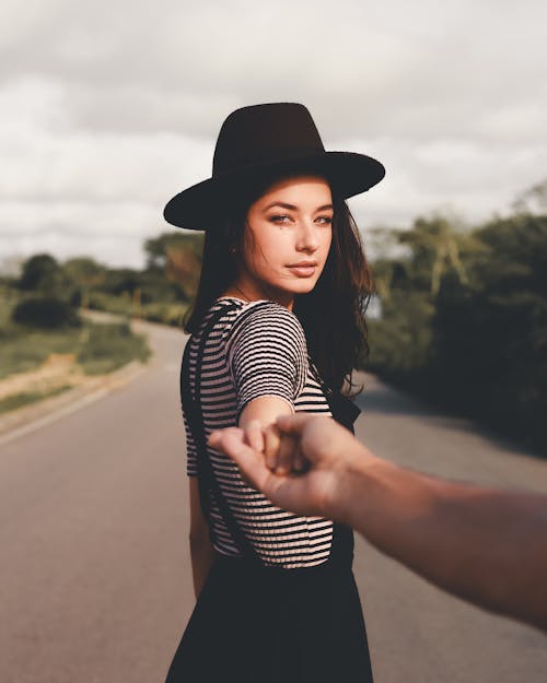 Woman in Black Hat Holding Person's Hand