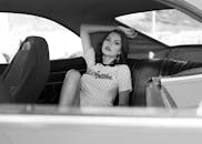 黑白肖像中，时尚女性在老爷车内摆出优雅姿态