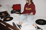 穿着连帽衫的少女在舒适的卧室里享受黑胶唱片