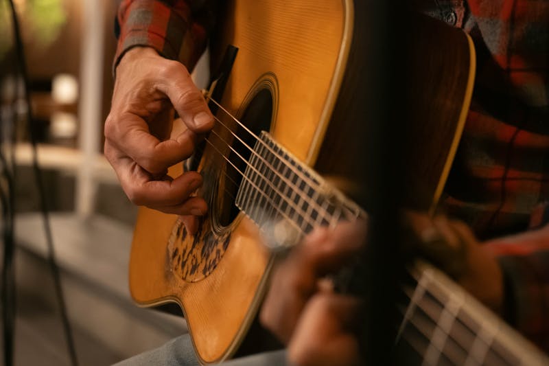 Detailed shot of hands playing acoustic guitar, showcasing musical expression.