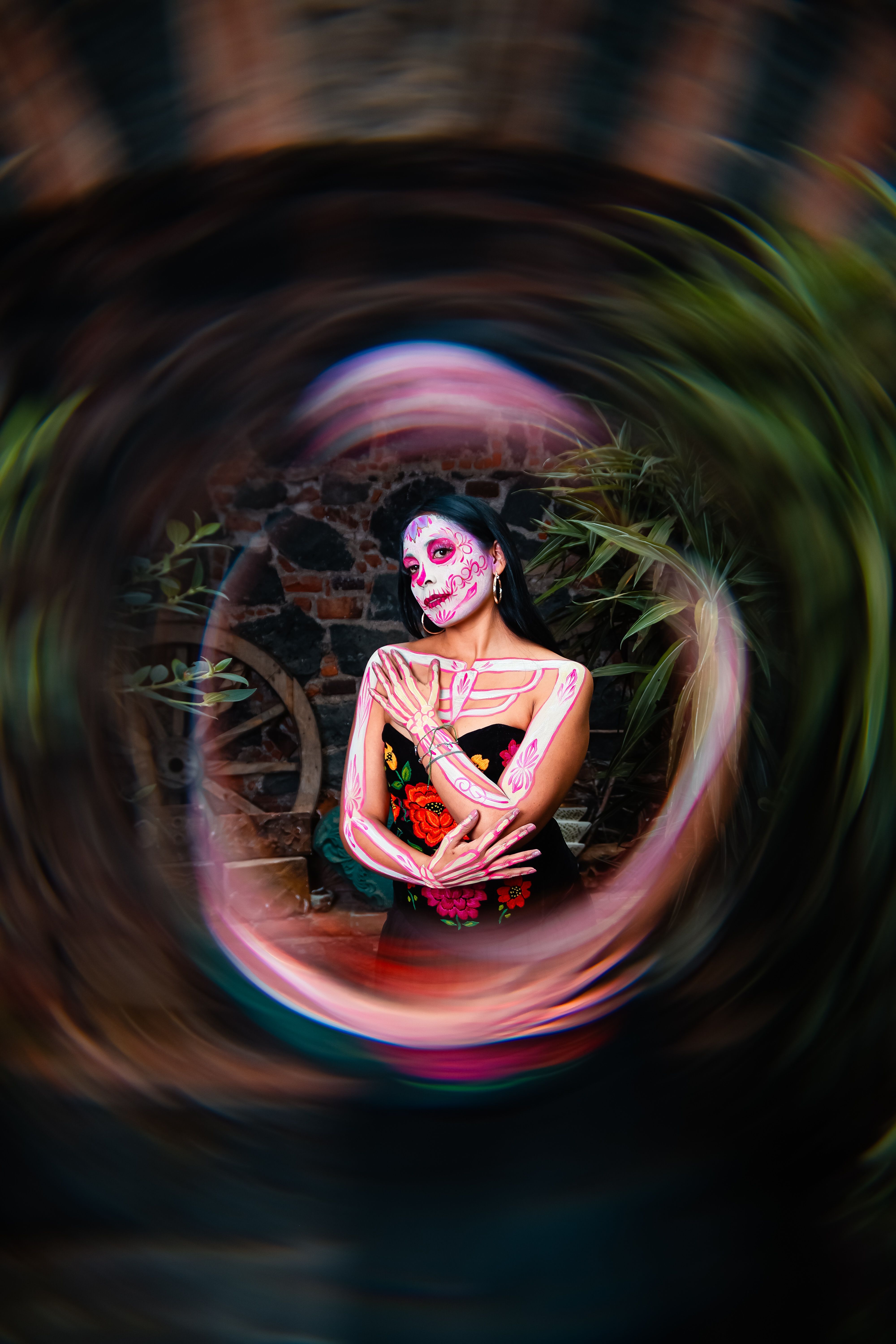 Vibrant portrait of a woman celebrating the Day of the Dead with artistic face paint in a dynamic setting.