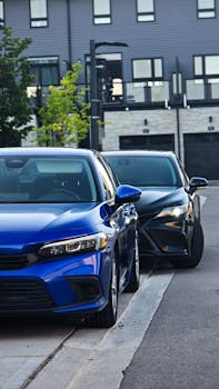 A blue and black car parked on a city street near modern buildings.