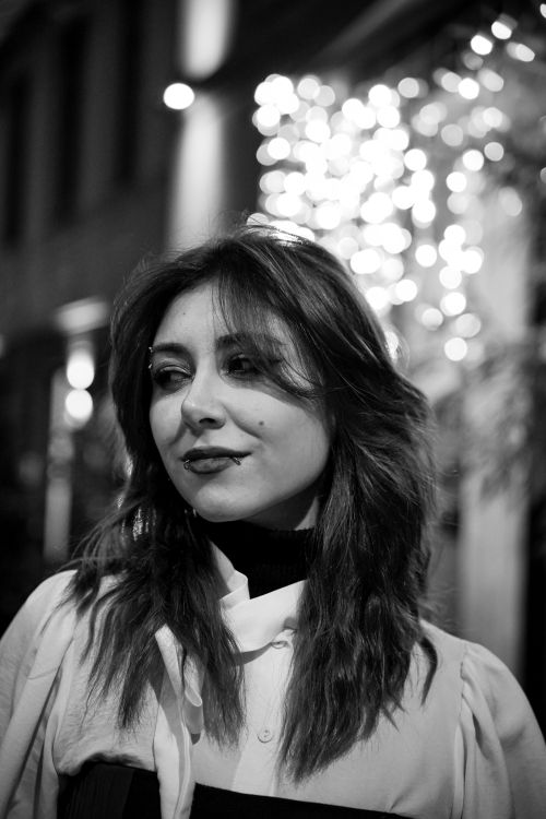Free Black and white portrait of a young woman outdoors at night with bokeh festive lights in background. Stock Photo