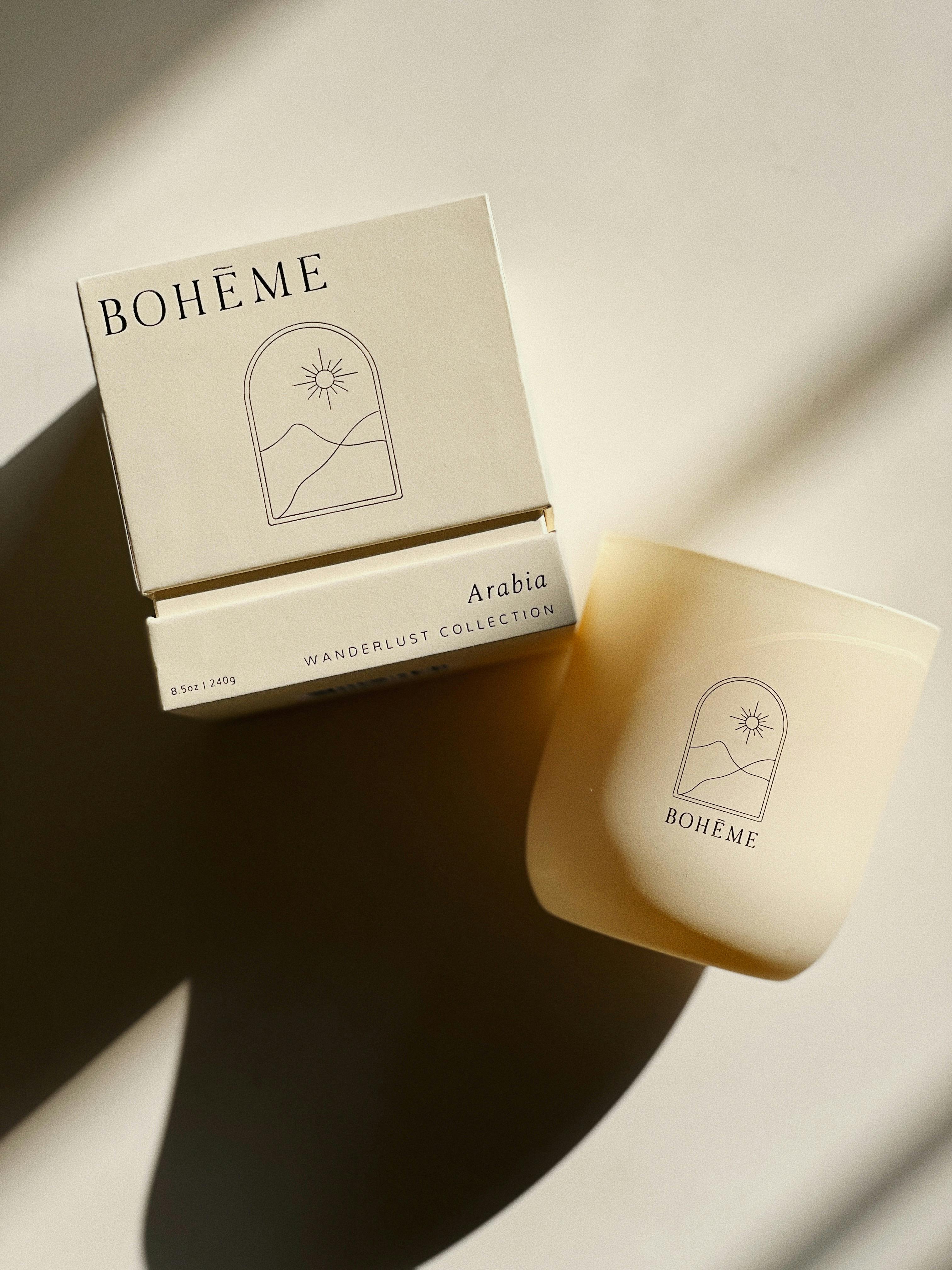 A classy Boheme candle with packaging on a sunlit beige background, evoking warmth and serenity.
