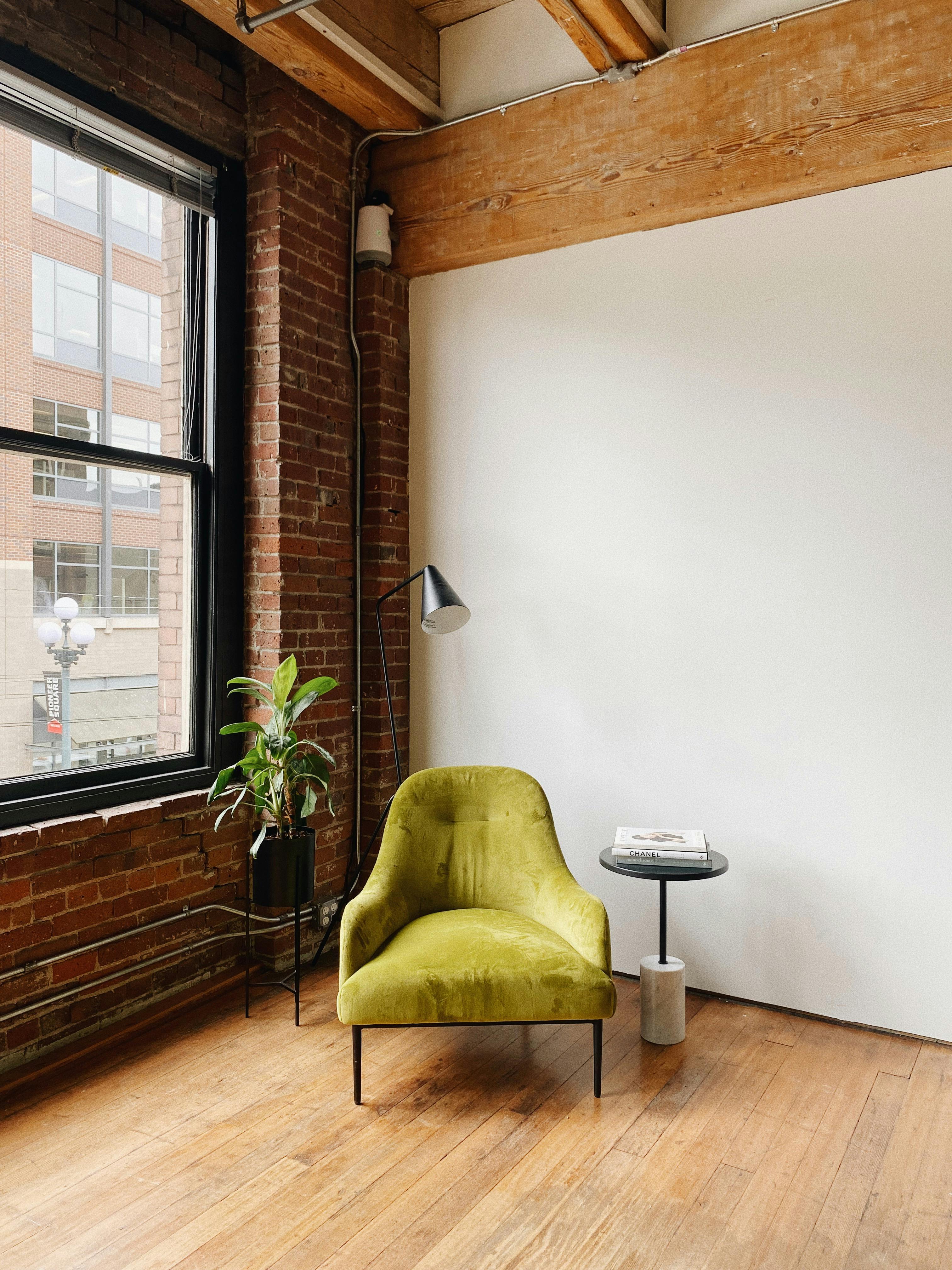 Modern loft interior with green chair, side table, and plant in Seattle. Cozy and stylish design.