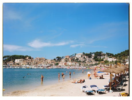 Vibrant summer day at the beach in Port de Sóller, Mallorca with people enjoying the sun and sea.