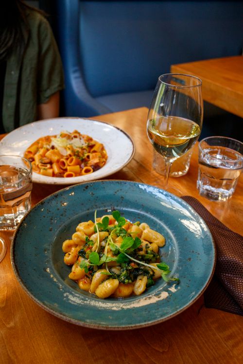 Free Close-up shot of Italian pasta dishes with white wine in a cozy restaurant setting. Stock Photo