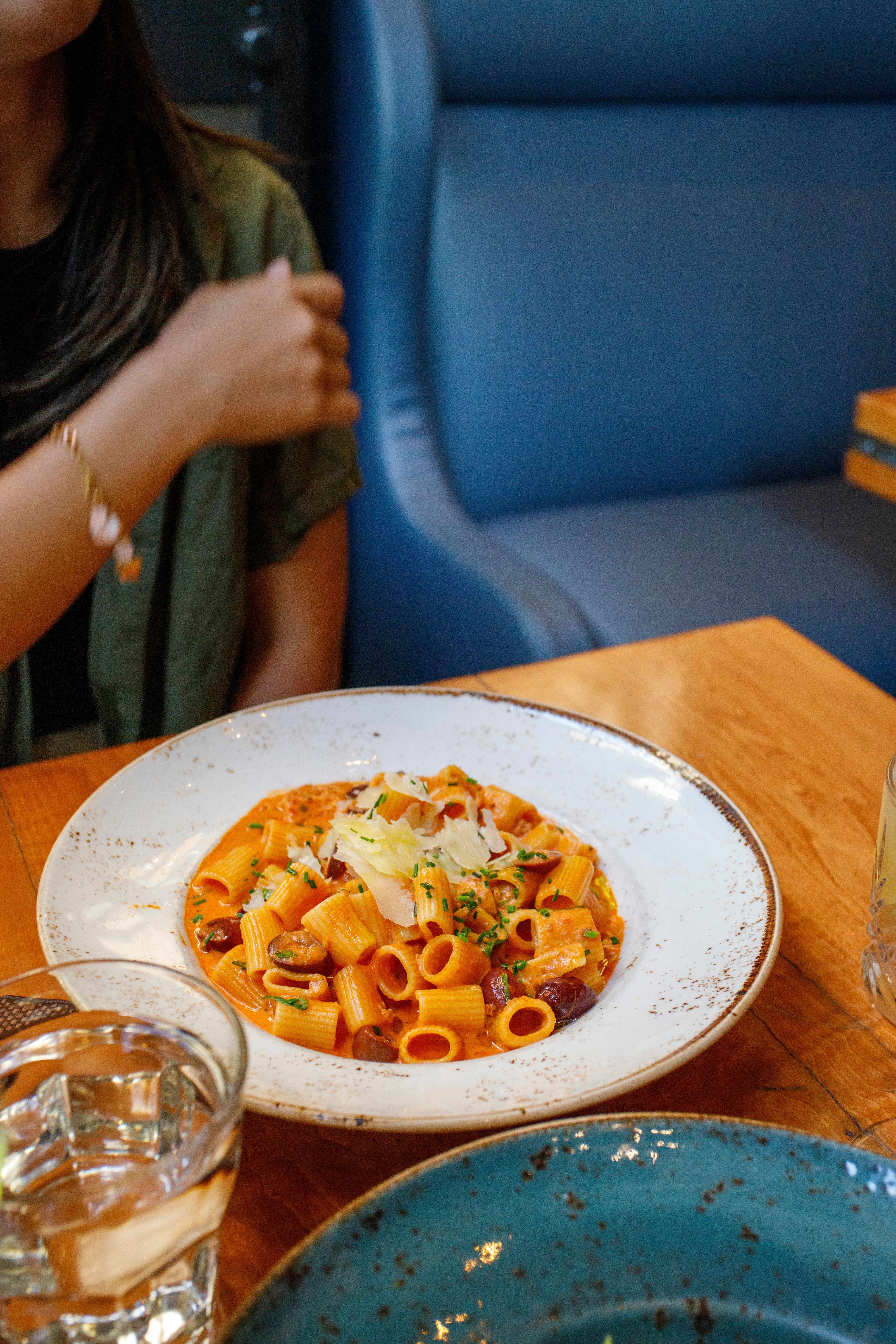 A flavorful rigatoni pasta dish with tomato sauce served on a wooden table in a cozy restaurant setting.