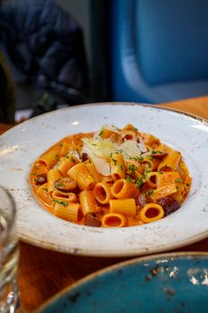 High-quality image of creamy rigatoni with olives and parmesan in a rustic setting.