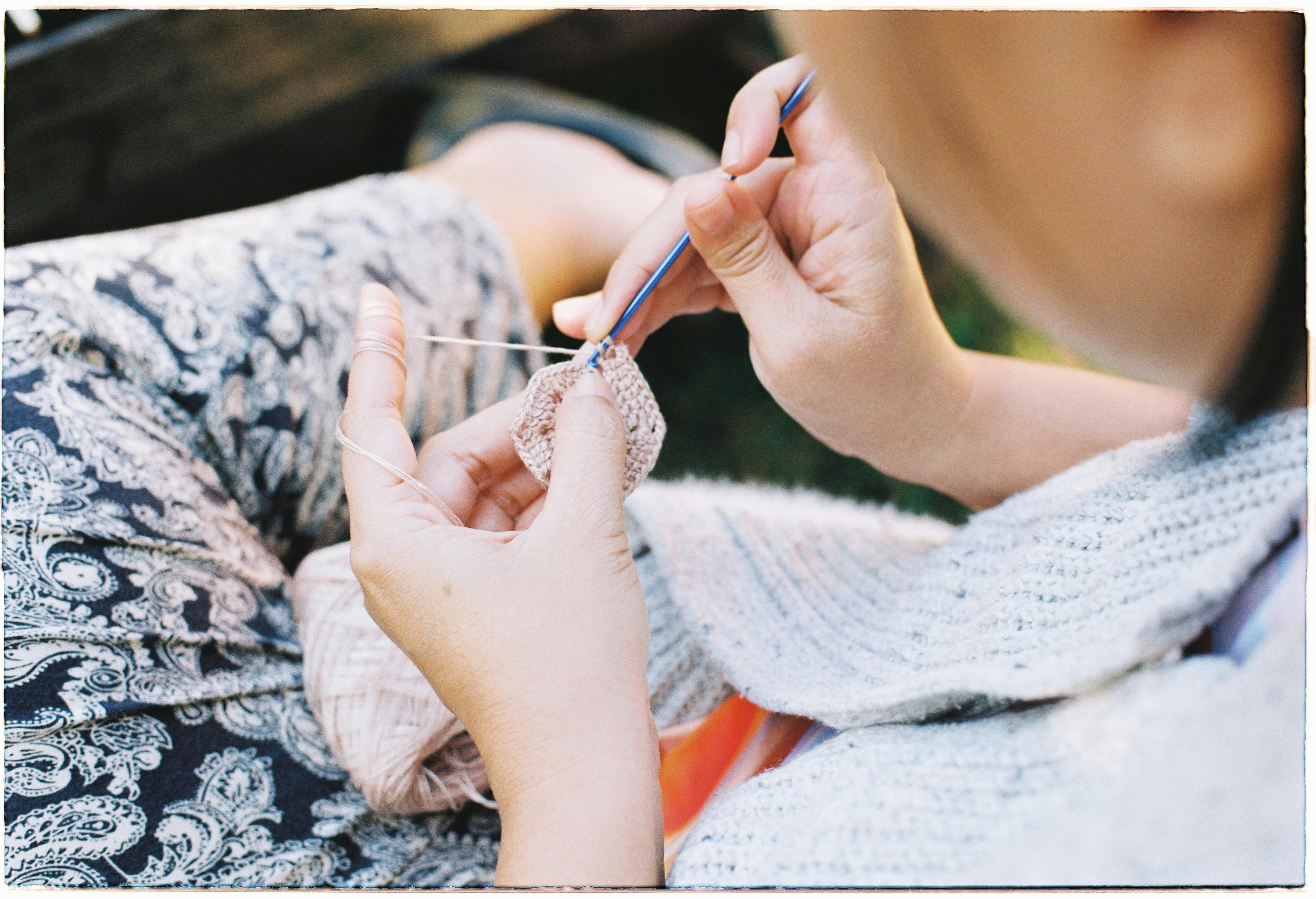 Woman crocheting outdoors, showcasing detail and texture in close focus. Perfect for craft and hobby themes.