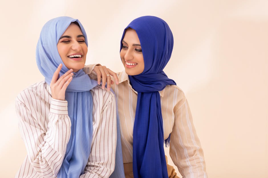 abaya from dubai online - Cheerful women in blue hijabs enjoying a light moment indoors.