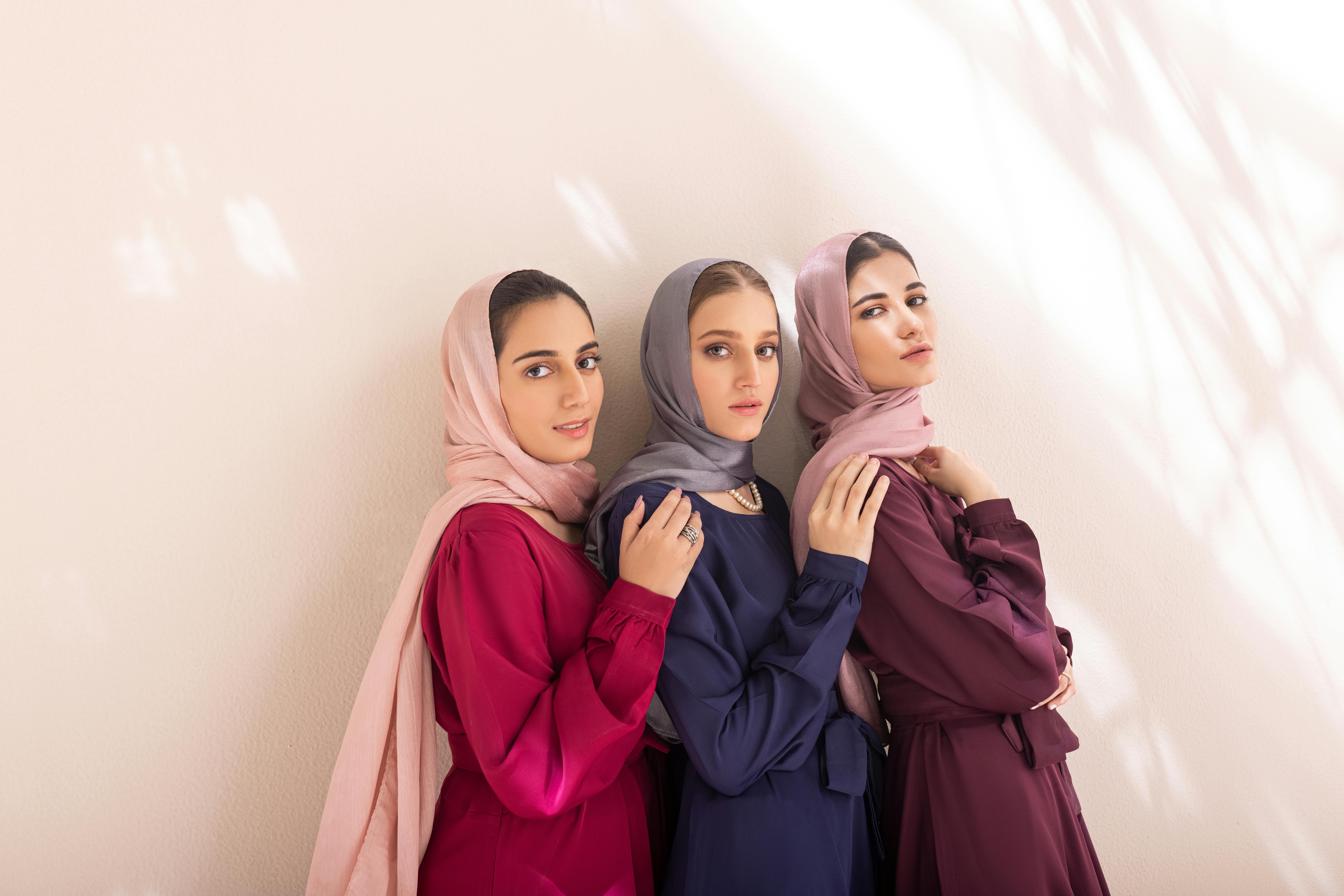 women green abaya headscarf set - Three women elegantly pose in stylish hijabs against a light backdrop.