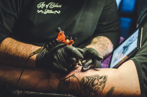 Free Tattoo artist creating detailed design on arm in studio setting. Stock Photo