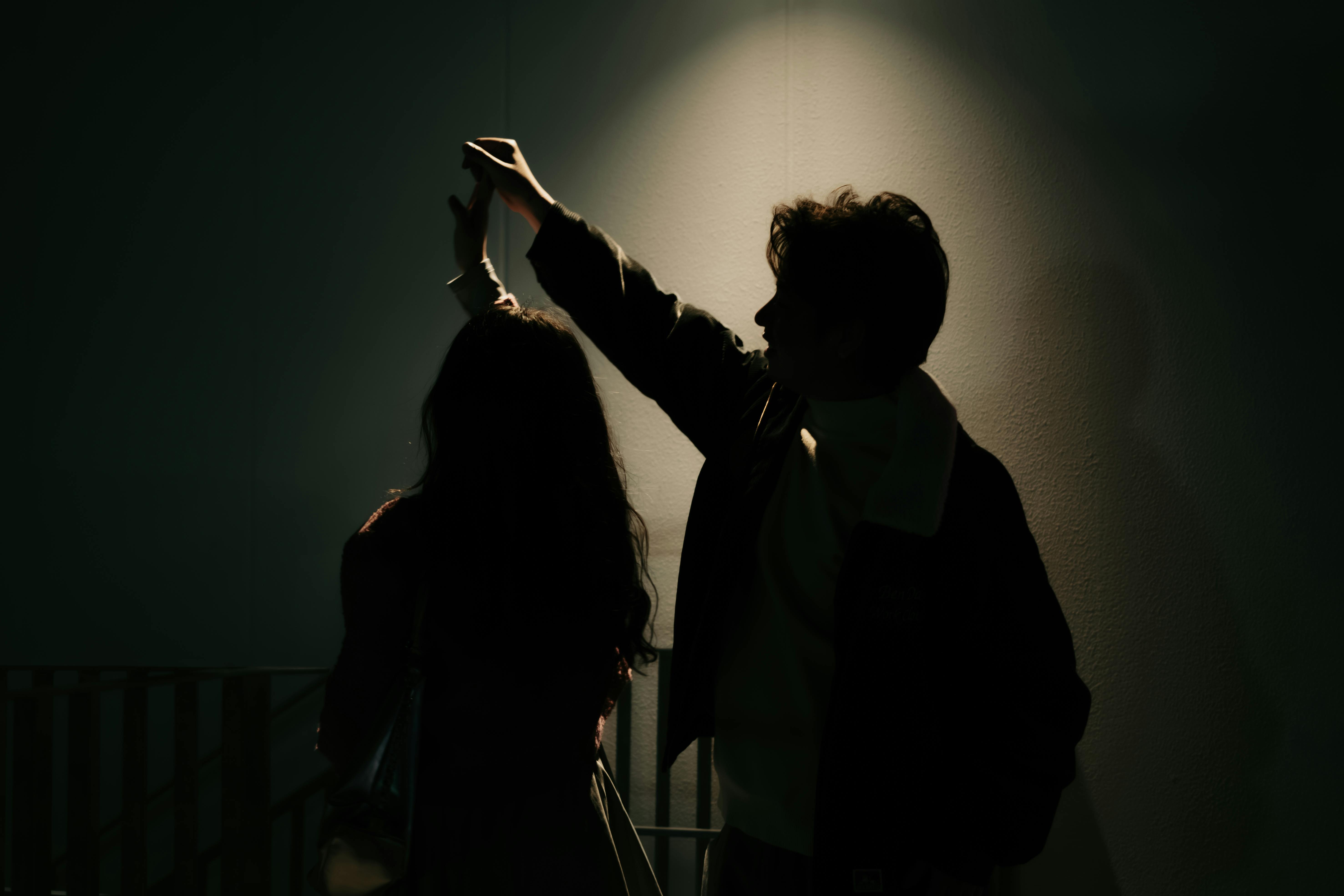 免费 一对情侣在戏剧性的灯光下手牵手的剪影，营造出浪漫的氛围。 素材图片