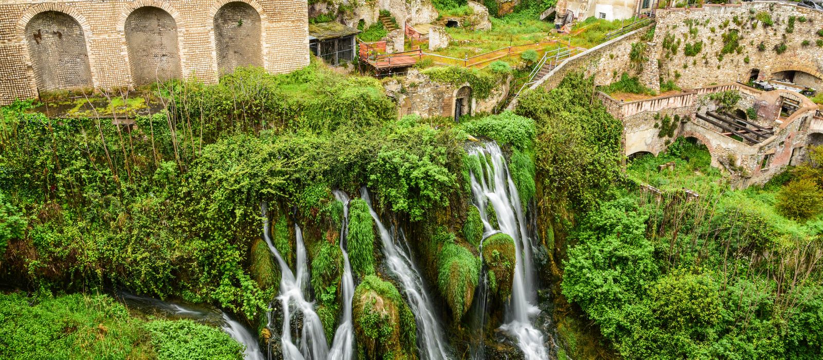 Captivating view of a waterfall amid ancient architecture in Tivoli, Italy.