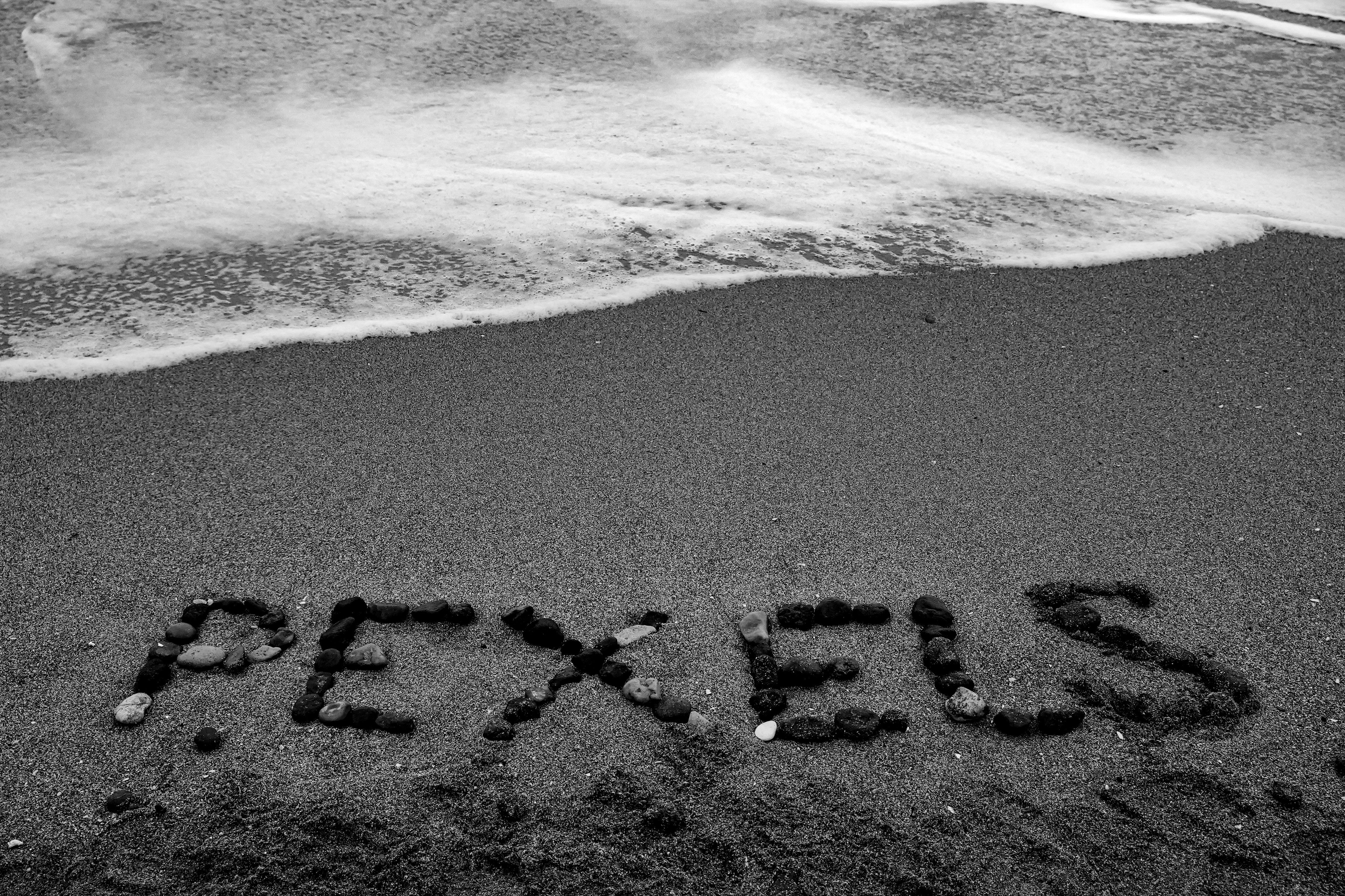 Black and white image of the word 'Pexels' written with stones on a beach in Şile, Istanbul.