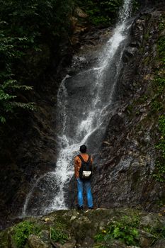 A lone hiker stands mesmerized by a tall waterfall in Hualien County, Taiwan.