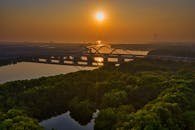 日落时分，从空中俯瞰雅加达的一座桥梁，水面倒影与四周郁郁葱葱的绿色植物构成了一幅令人惊叹的画面