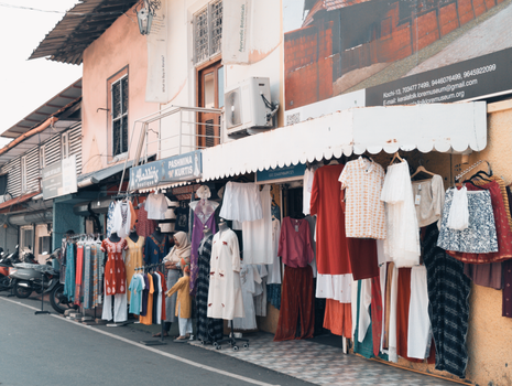 Vibrant street market featuring diverse clothing on display in an urban setting.